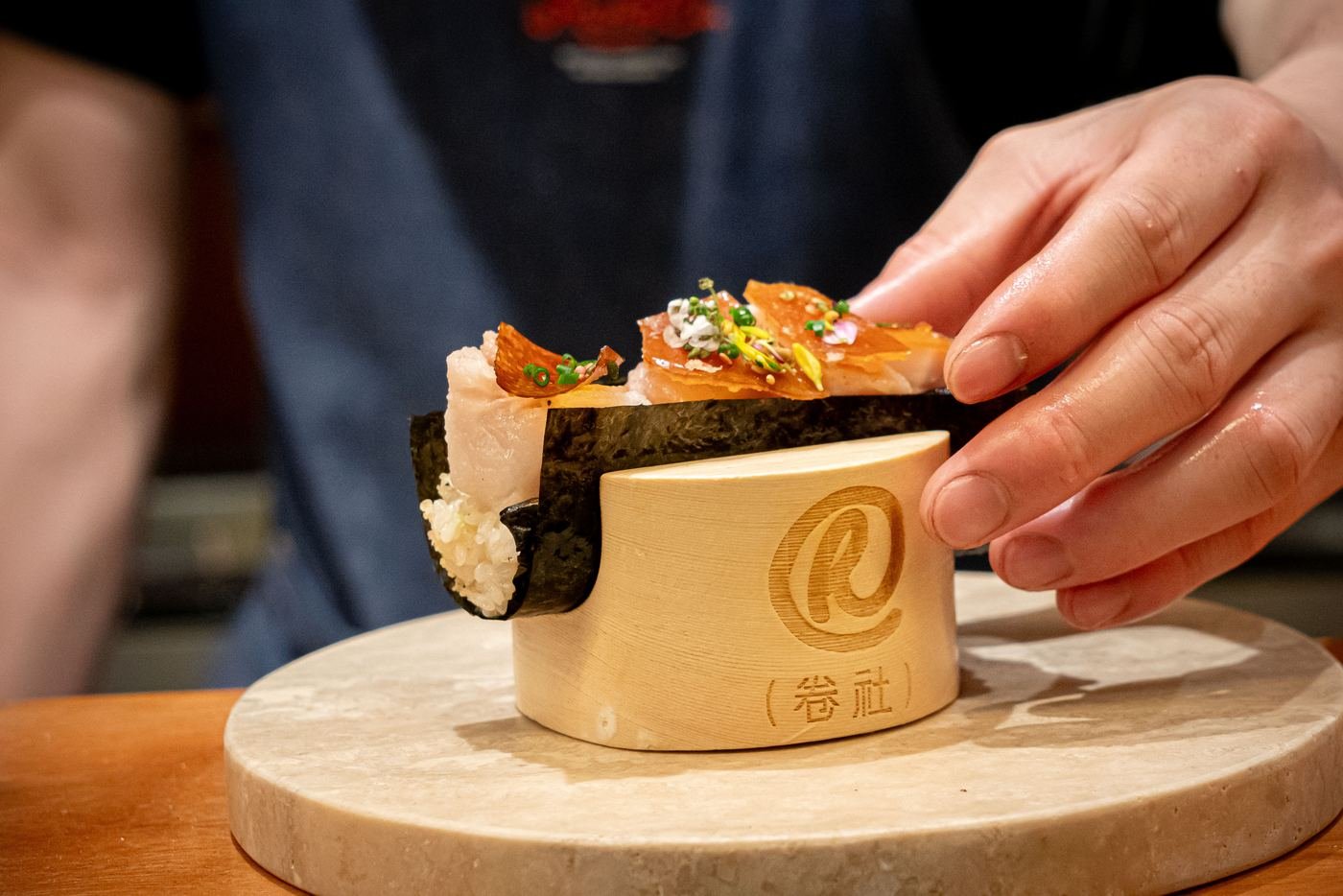 Hand roll being stamped with the Roll & Co. mark